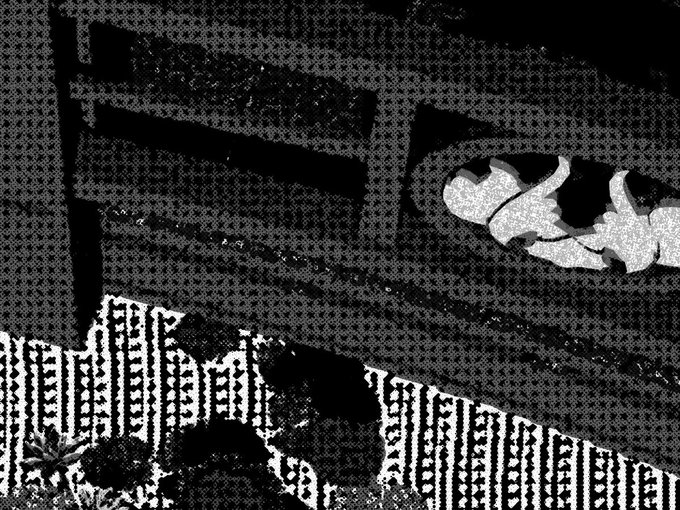 A grainy black-and-white image shows a person partially visible behind a railing, wearing a shirt with large text.