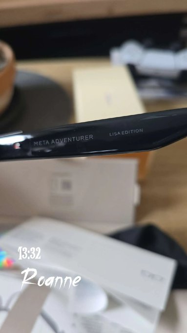 A close-up shot of black eyeglass temples engraved with 'META ADVENTURER' and 'LISA EDITION', with handwritten text '13:32 Roanne' in the corner.