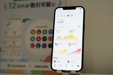 The image features a smartphone sitting on top of a wooden surface, with its screen displaying data about cryptocurrency prices. The phone's design is sleek and modern, suggesting that it may be made by a Japanese company such as Panasonic or Mitsubishi. A banner at the bottom right corner of the image announces the presence of a new listing for cryptocurrency coins, including Shiba Inu, which could possibly interest users who are interested in crypto trading.