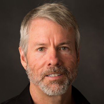 The image shows a man with gray hair wearing a black shirt who appears to be smiling at the camera. Below him, there is a caption that talks about Bitcoin hitting $950,000 and waiting for its price to drop before investing, which can potentially double or triple in value if it takes off. The post seems related to the Bitcoin market and mentions specific moments when Bitcoin has reached certain points of interest.