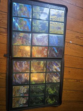 A binder page displaying a collection of holographic Pokémon trading cards laid out in rows.