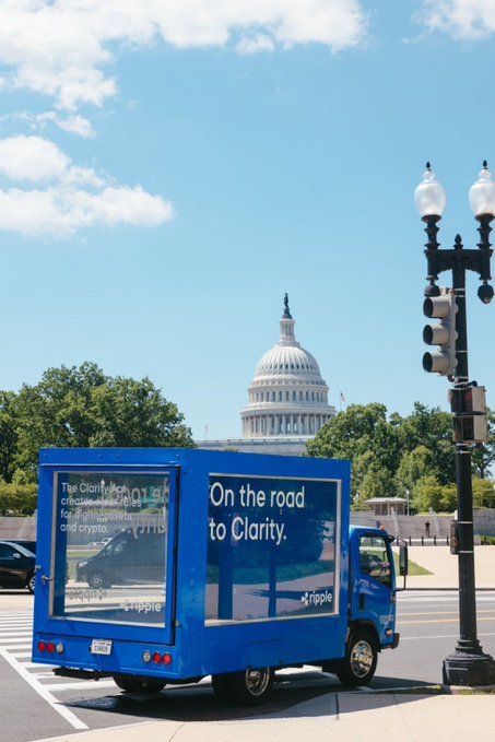 A blue Ripple-branded truck drives past the U.S. Capitol building with the slogan "On the road to Clarity" and messaging about creating new utility for digital assets like XRP, visually reinforcing the post's message that regulatory clarity for crypto is on its way.