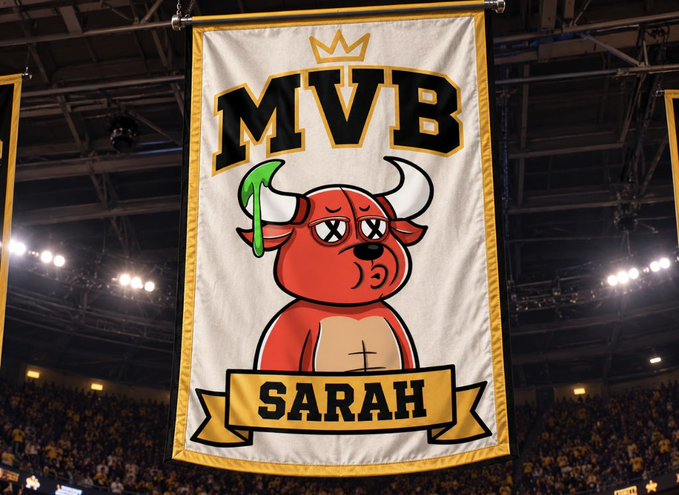 A championship banner hanging in an arena featuring a red bull mascot with X eyes, topped with a crown, and labeled 'MVB' and 'SARAH' on a ribbon.
