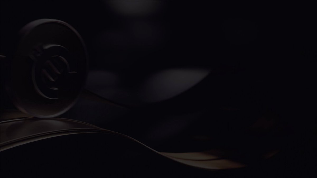 The image features a black background with an object, possibly a coin or a key, placed at the center of the frame. The object appears to be a small metal disc with a logo on its top side. The background has a dark color that contrasts with the object and makes it stand out prominently in the image.