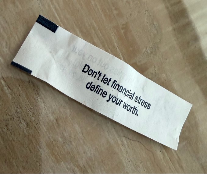 The image features a fortune cookie with a message written on it that reads "Don't let financial stress define your worth." This message seems to be related to the post about gambling, as indicated by the use of the word "hope" in one sentence and the phrase "I bought Ripple" in another. The fortune cookie is placed on a table or countertop, which could be a dining table or any other flat surface.