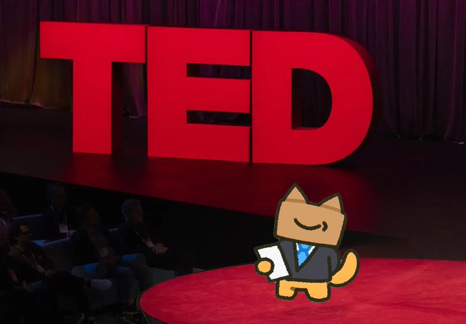 The iconic red TED stage sign on a stage with an audience seated, featuring a cartoon fox mascot in a suit in the foreground.