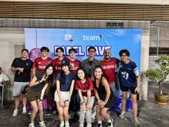 A group photo of about ten young people posing in front of a 'UZ team' and 'SHOW LOVE' banner in an indoor setting.