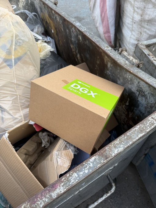 A NVIDIA DGX Spark box being thrown into or dumped in a metal dumpster among trash bags and cardboard boxes.