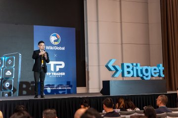 Lewis, Chief Market Analyst at UEX, delivers a keynote presentation on stage at WikiEXPO, with "WikiGlobal," "UEX," and "Bitget" branding visible on the screen and podium behind him to a seated audience.