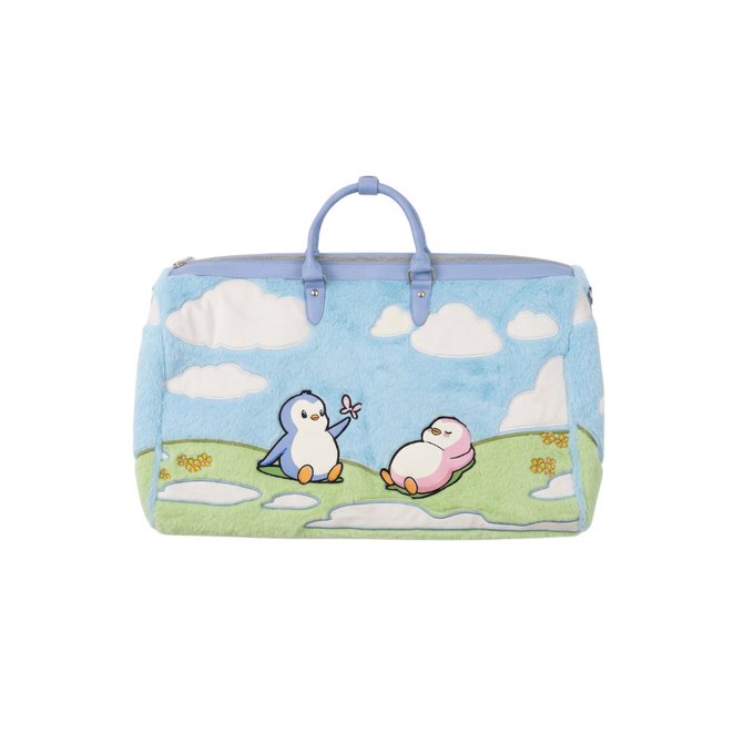 A light blue, fluffy travel bag featuring a cute design of two penguins on green grass under a cloudy sky, with blue top handles and a zipper.
