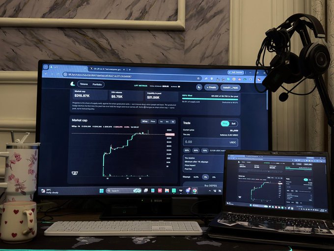 A cryptocurrency trading setup on a desk, showing a main monitor and a laptop both displaying a trading interface with a price of $319.97K.