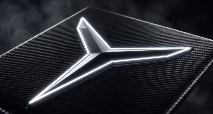 A close-up of a glowing, futuristic silver star emblem on a dark, textured surface, resembling a logo or insignia.