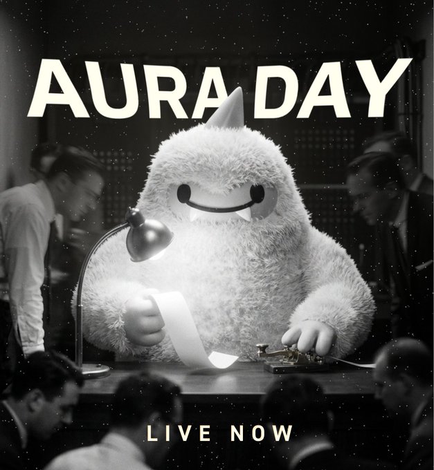 A black and white image of a cute fluffy creature at a desk typing on a typewriter, with 'AURA DAY' at the top and 'LIVE NOW' at the bottom.