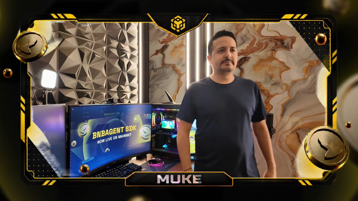 The image features a man standing next to two computer monitors with the word "Muke" written above them. The background of the image shows a clock and a gold frame surrounding the scene. There are also some clocks visible, one on top of another, suggesting that this is an event or gathering related to timekeeping.