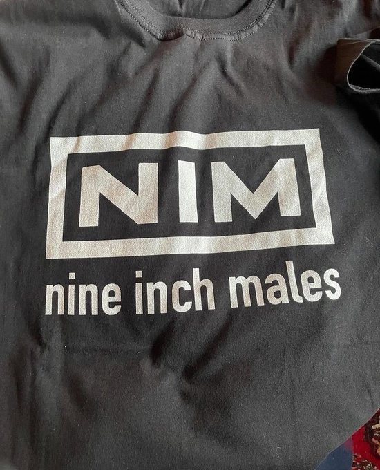 A black t-shirt features a parody logo in a white rectangle reading 'NIM' with 'nine inch males' written underneath, mimicking the Nine Inch Nails band merchandise.