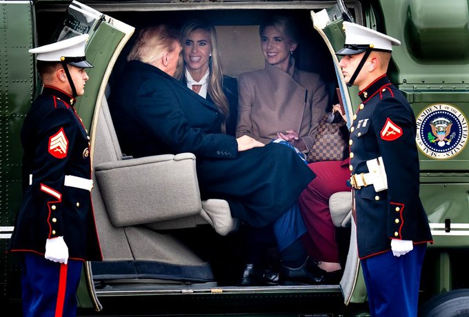 Donald Trump, Ivanka Trump, and Melania Trump sit inside Marine One helicopter flanked by two US Marines in dress uniform with white gloves at the doorway.