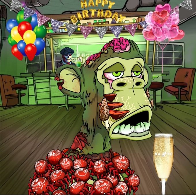 A cartoon illustration of a grotesque zombie head with exposed brain emerging from a pile of red-wrapped candies, with 'HAPPY BIRTHDAY' banners, balloons, and a champagne glass labeled 'BADZ' in the background.