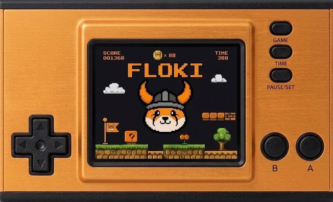 An orange handheld gaming device displays a retro platformer game featuring "FLOKI" as the title, with a pixelated Shiba Inu character wearing a Viking helmet, alongside a score of 001368, 88 coins, and a timer of 388. The image visually reinforces the post's "FLOKI FOREVER" message by portraying the FLOKI meme coin mascot in a nostalgic, building-block style game screen, symbolizing the project's ongoing development and growth.