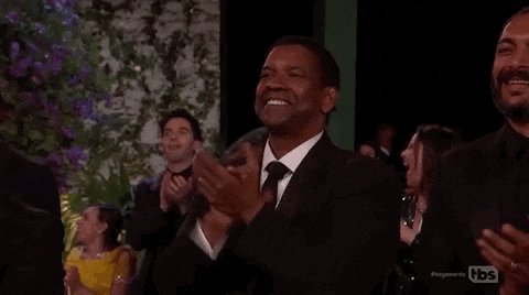 iced tea and a purple flower are present on the table, with two men clapping hands in front of them.