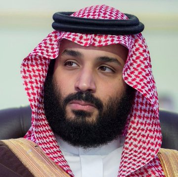 A close-up photo of a man with a beard wearing traditional Saudi Arabian attire, including a red and white checkered keffiyeh with a black agal.
