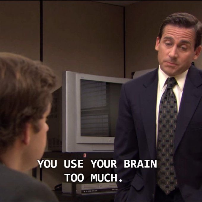 A screenshot from The Office showing Michael Scott (Steve Carell) in a suit looking down at an employee, with the subtitle 'YOU USE YOUR BRAIN TOO MUCH.'