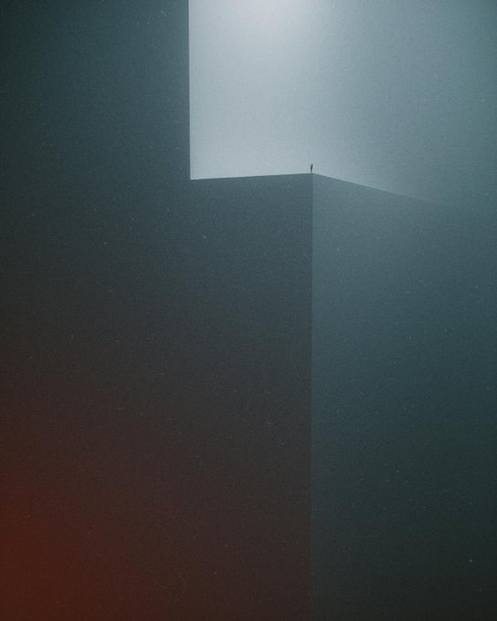 A dark, atmospheric minimalist image showing a tiny silhouette of a person standing on the edge of a tall geometric structure against a foggy, light-filled sky.