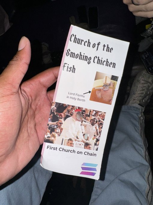 A hand holds a flyer titled 'Church of the Smoking Chicken Fish' advertising 'Lord Fishnu in Holy Birth' at the 'First Church on Chain'.