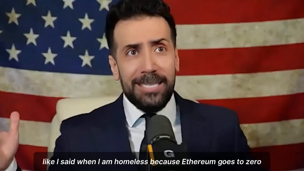 The image features a man wearing a suit, sitting behind a microphone with his hands on his lap. He has a beard and mustache, giving him a distinguished appearance. The background of the image is an American flag, which adds to the overall theme of the scene. The caption below the image reads "What are your plans when Ether goes to zero?".