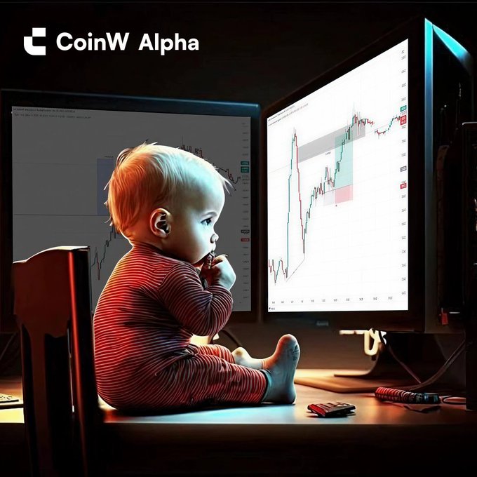 A CoinW Alpha promotional image showing a baby in striped pajamas sitting at a desk, studying candlestick trading charts displayed on two large monitors.
