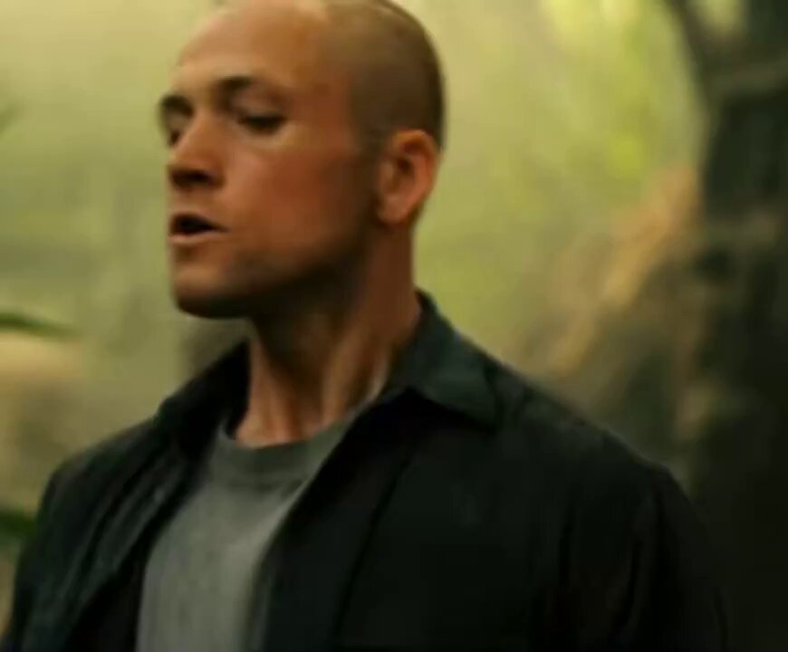 The image features a bald man wearing a black jacket, standing against a green background with trees visible behind him. The caption of the image reads "4 hours of sleep ⟶ loads of client work to do ⟶ loads of outreach to do ⟶ still $0 in loss on Polymarket ⟶ $ETH & $ADA shorts are in profits". This suggests that the man is a businessman who has been working hard and making money. The green background with trees indicates that he might be in an outdoor setting, possibly near a forest or park area.