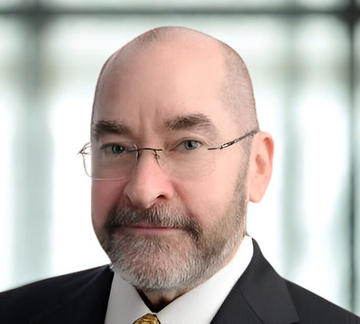 The image shows a man dressed in a suit, looking serious while posing for the picture. He has glasses on his face and appears to be balding. In the background, there are blurred windows that can be seen clearly without much detail or obstruction, providing an interesting visual element to the overall composition of the scene. There is also text in the image which reads: "JUST IN: $15 Billion investment bank TD Cowen analyst Lance Vitanza has reiterated buy rating on #bitcoin treasury company Strategy". This piece of information likely relates to the man's position as a financial expert or a trader, further supporting the relevance of his appearance and the context of the scene.