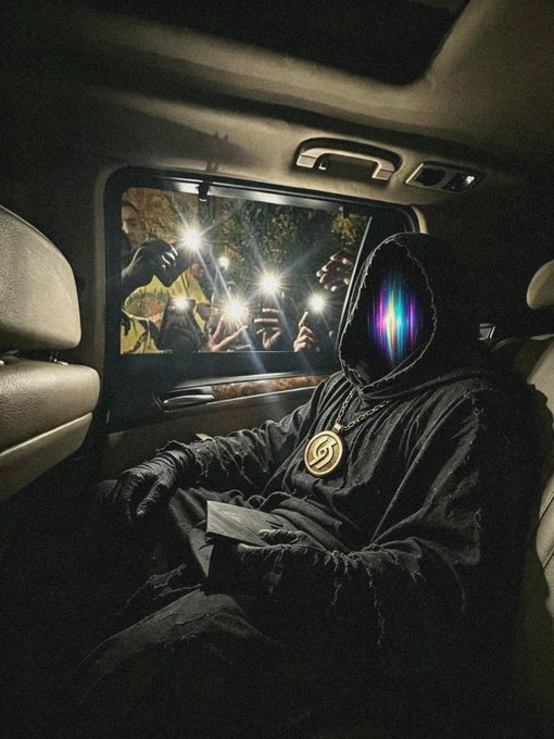 A hooded figure with a glowing rainbow-colored face and a gold 'S' medallion sits in the back of a vehicle while people outside point phone flashlights through the window.