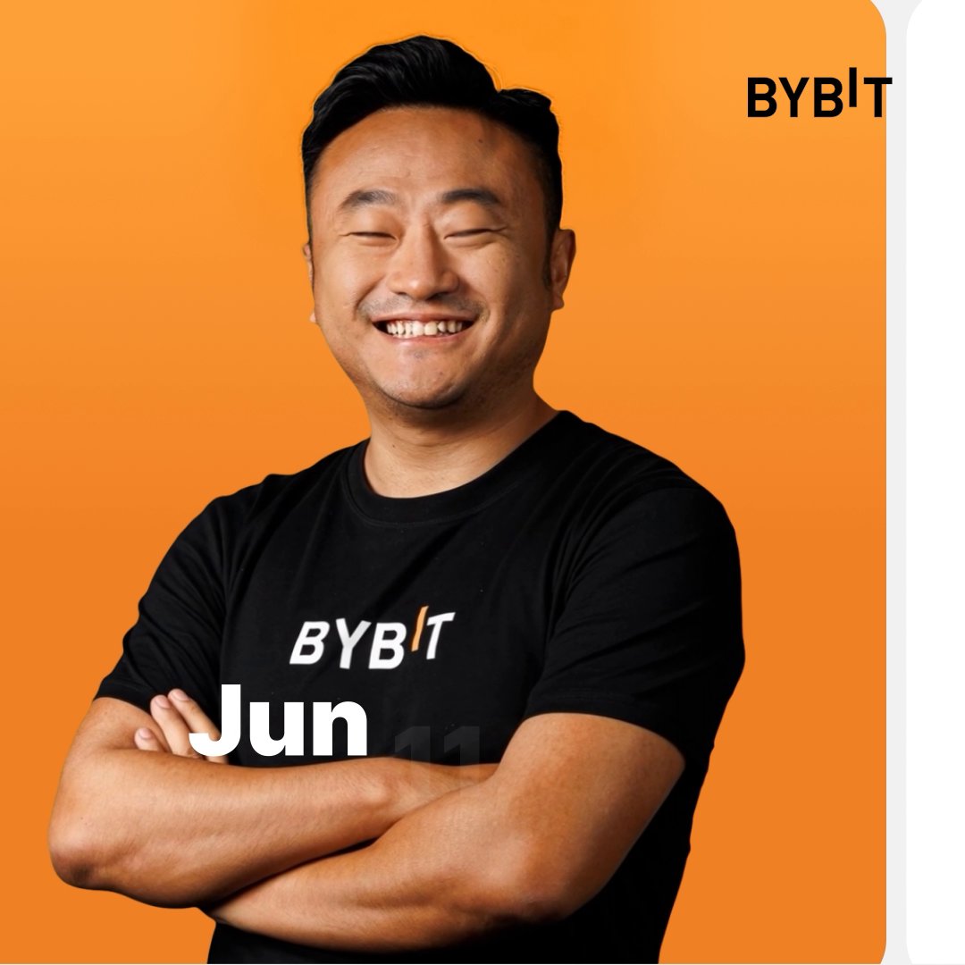 A smiling man wearing a black t-shirt has crossed his arms and appears ready to pose for a photo against an orange background that says "BYBIT Jun" at the bottom. The man's facial expression suggests he is happy or relaxed, possibly enjoying being featured in a picture with Bybit as part of their event promotion. His cheerful mood aligns well with the vibrant orange backdrop, creating a visually appealing and energetic atmosphere for the photo.