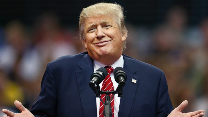 President Donald Trump is pictured here at a podium. The image relates to the breaking news that he has stated the US is considering purchasing Bitcoin and other cryptocurrencies on a "substantial scale."