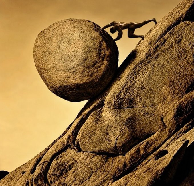 A sepia-toned surreal image showing a small figure pushing a massive boulder up a steep rocky slope.