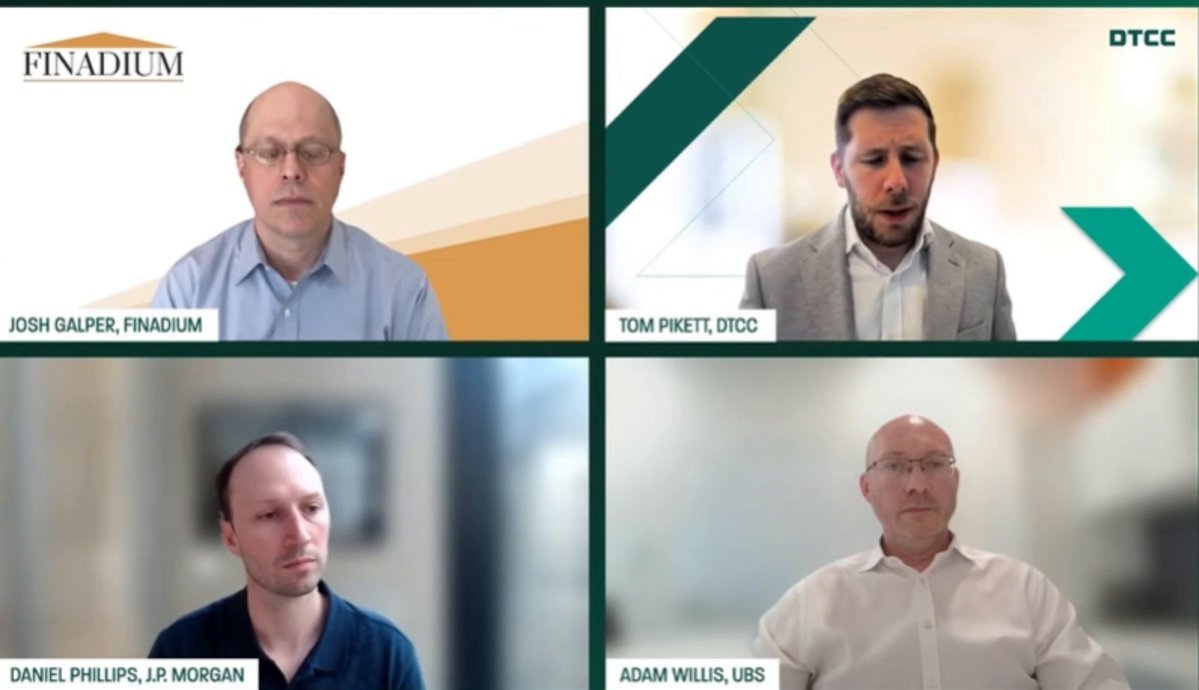The image shows four men sitting behind a table, each wearing glasses and looking at their computer screens. They appear to be engaged in a video conference call with the text "DTCC will move $XLM and $XRP tokenized DTC-custodied assets connecting to Stellar Multi-chain bridge infrastructure. The quiet part is now public." displayed on the screen, indicating that they are discussing financial matters or sharing information related to cryptocurrency trading.