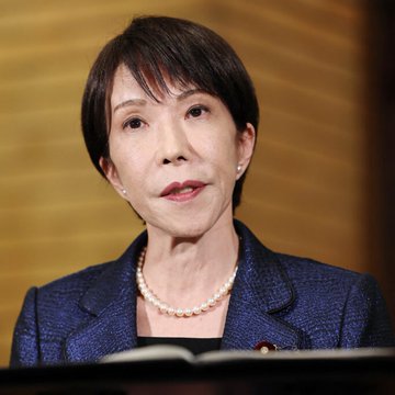 The image shows a woman in a suit and pearl necklace, likely a politician or businessperson, speaking at a podium. The accompanying text suggests a potential XRP spike relating to a "Reverse Carry" strategy in finance.