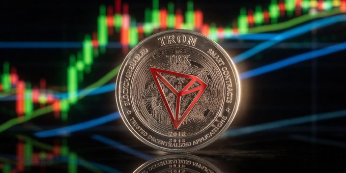 The image features a coin with a red triangle design on its surface, which appears to be made of metal or stone. The coin has a shiny appearance, suggesting that it might have been polished recently. The background of the image consists of a blurred line graph, indicating that the photo was taken in an office setting where financial data is being displayed. The text "TRON Đâm thật nhưng nhìn kỹ dữ liệu 2026 sẽ hơn rất nhiều" can be seen, which is likely a part of the post's title or caption. The coin and its background are placed in the center of the image, drawing attention to their unique features.