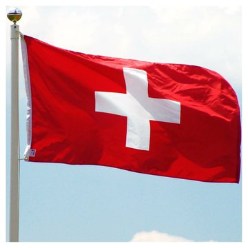 The Swiss flag waves against a blue sky, its bold white cross on red symbolizing Switzerland's emergence as a major global crypto hub with 1,766 blockchain companies and streamlined regulation from FINMA.