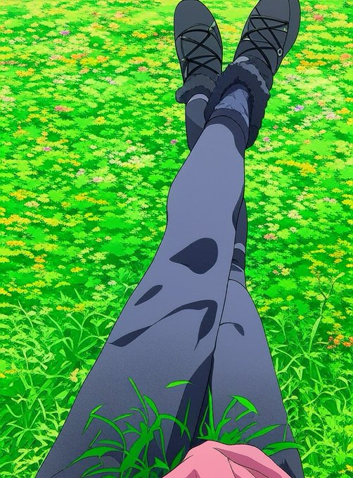 An anime-style illustration showing a first-person view of a person's legs in grey leggings and black shoes, stretching up against a background of green grass and small white flowers.