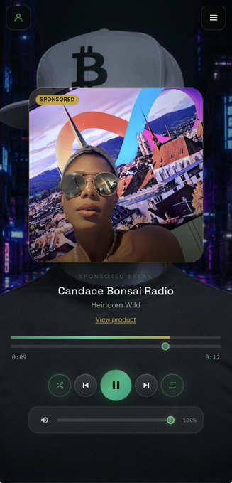 A screenshot of a Spotify radio app displaying a sponsored break for "Candace Bonsai Radio" featuring Heirloom Wild, with album art showing a woman in sunglasses against a mountainous backdrop. The post humorously suggests that the woman pictured in the sponsored advertisement has unexpectedly appeared while the user was listening to content about Dfinity.