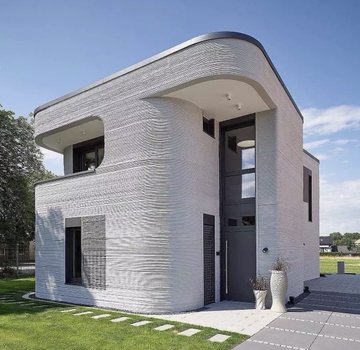A modern, two-story house with distinctive wavy white textured exterior walls, featuring a curved roofline, dark windows, and set on a green lawn.