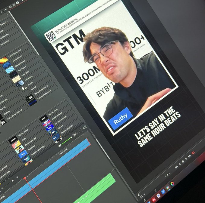 A computer monitor displays a video editing workspace with a WEBINAR panel showing a man with glasses, labeled "Ruthy" and titled "GTM 300M BYBIT," alongside a caption reading "LET'S SAY IN THE SAME HOUR BEATS." The image connects to the post by showing Ruthy, the person tagged by the author, appearing in a professional webinar setting about achieving 300M, playfully framed as a friendly "not mean" moment.
