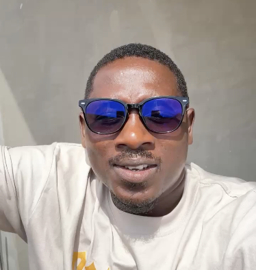 A man wearing reflective blue sunglasses and a white t-shirt smiles confidently at the camera, projecting optimism that aligns with the post's enthusiastic message about new beginnings and fresh opportunities for wealth in the coming week and era.