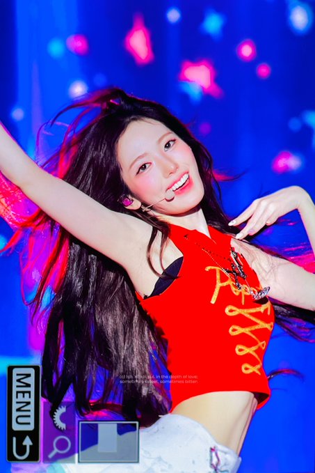 A female K-pop idol performing on stage in a red top with gold accents, with overlay text including 'MENU' and 'POPSTAR'.