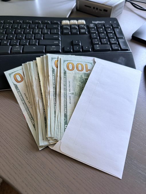 A fan of $100 US bills sits on a desk in front of a Logitech keyboard, next to a white envelope. The image relates to the post's question about an Ethereum project that automatically refunded deposits, visually representing the idea of getting money back.