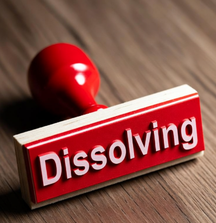 A red rubber stamp displaying the word "Dissolving" sits on a wooden surface, symbolizing the concept of ending or terminating something. The image visually reinforces the post's consideration of dissolving a 2-year/8-year $ICP neuron, as holding long-term staking positions may become less appealing with DeFi options emerging.