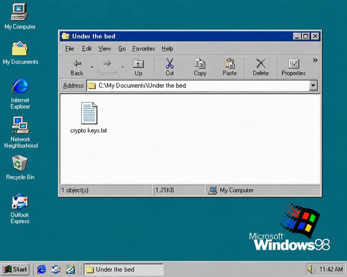 A Windows 98 desktop displays a folder titled "Under the bed" containing a file called "crypto keys.txt," humorously suggesting a safe place to store cryptocurrency keys—though the accompanying post jokingly recommends Evernote instead. The Microsoft Windows 98 logo is visible in the bottom right corner, with the time showing 11:42 AM.