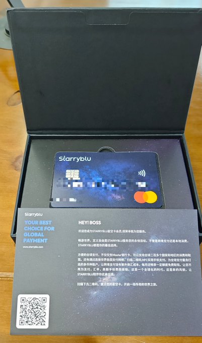 An open black box containing a 'Starryblu' branded card with a galaxy design and Mastercard logo, alongside a welcome card addressed to 'HEY! BOSS' about global payment services.