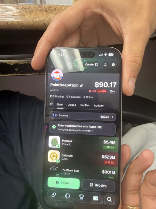 A hand holds a phone displaying a crypto/trading app profile for "PaintDeepAtom" showing a $90.17 balance with holdings in Pistacio ($5.4M), Catcoin ($57.3M), and The Black Bull ($301M), illustrating the post's joke about a newly onboarded "normie" friend being drawn into the chaotic meme coin trenches on pump.fun.